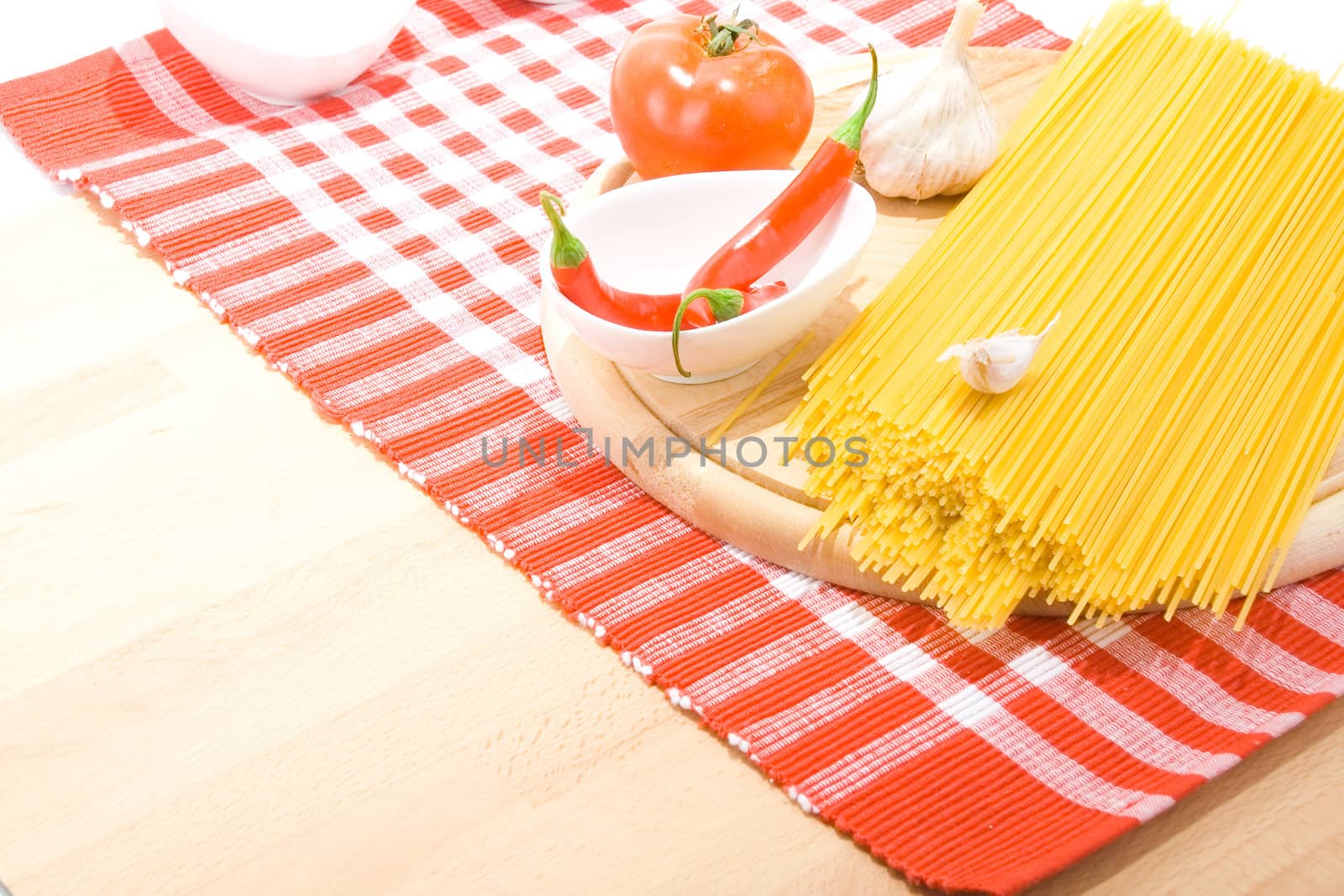 Golden raw dried Italian pasta with other ingredients on kitchen desk. 