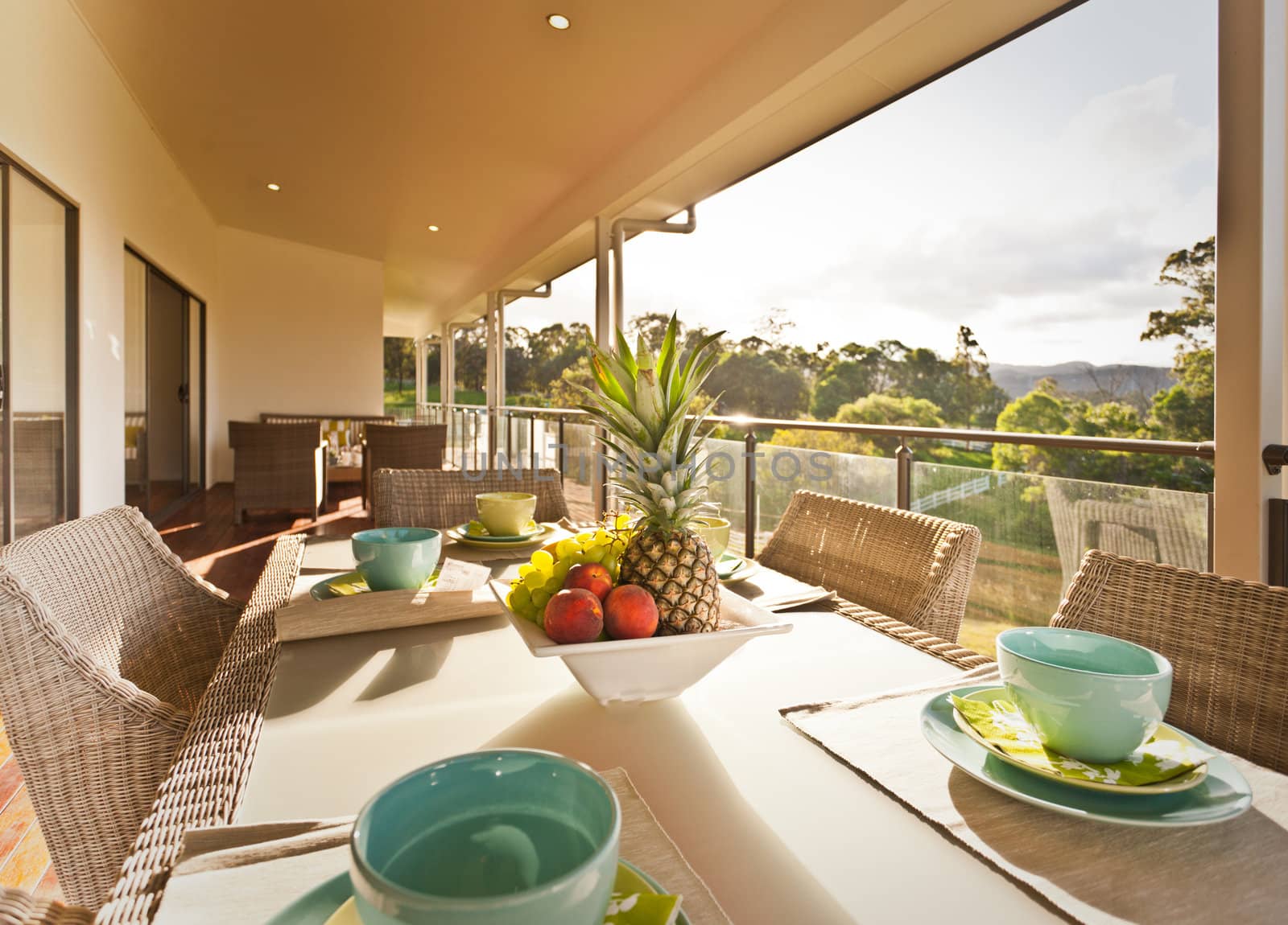 Elegant outdoor table setting with a central bowl of tropical fruit on an open verandah overlooking a rural garden