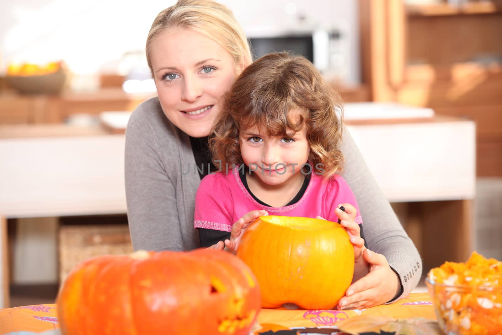 Mother and daughter decorating pumpkins by phovoir