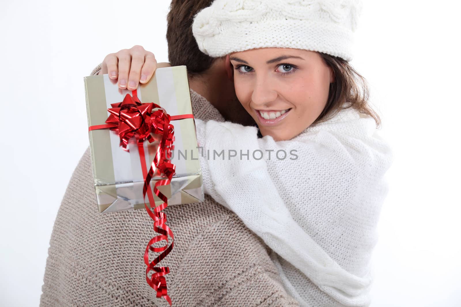 Young couple hugging with a wrapped present by phovoir