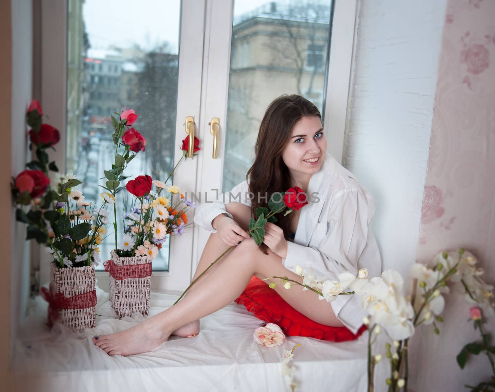 beautiful woman in the flowers on the windowsill