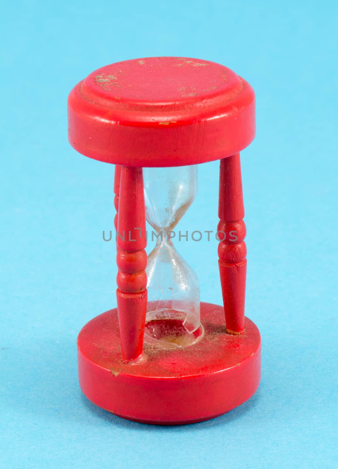 broken red retro object sand glass clock on blue background.