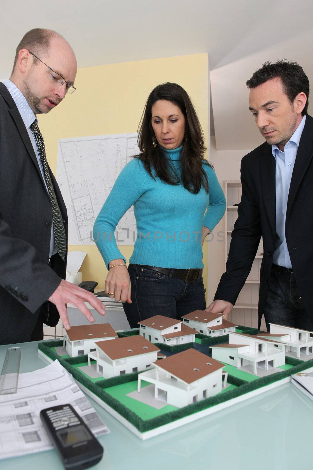 Couple with an architect looking at a housing model