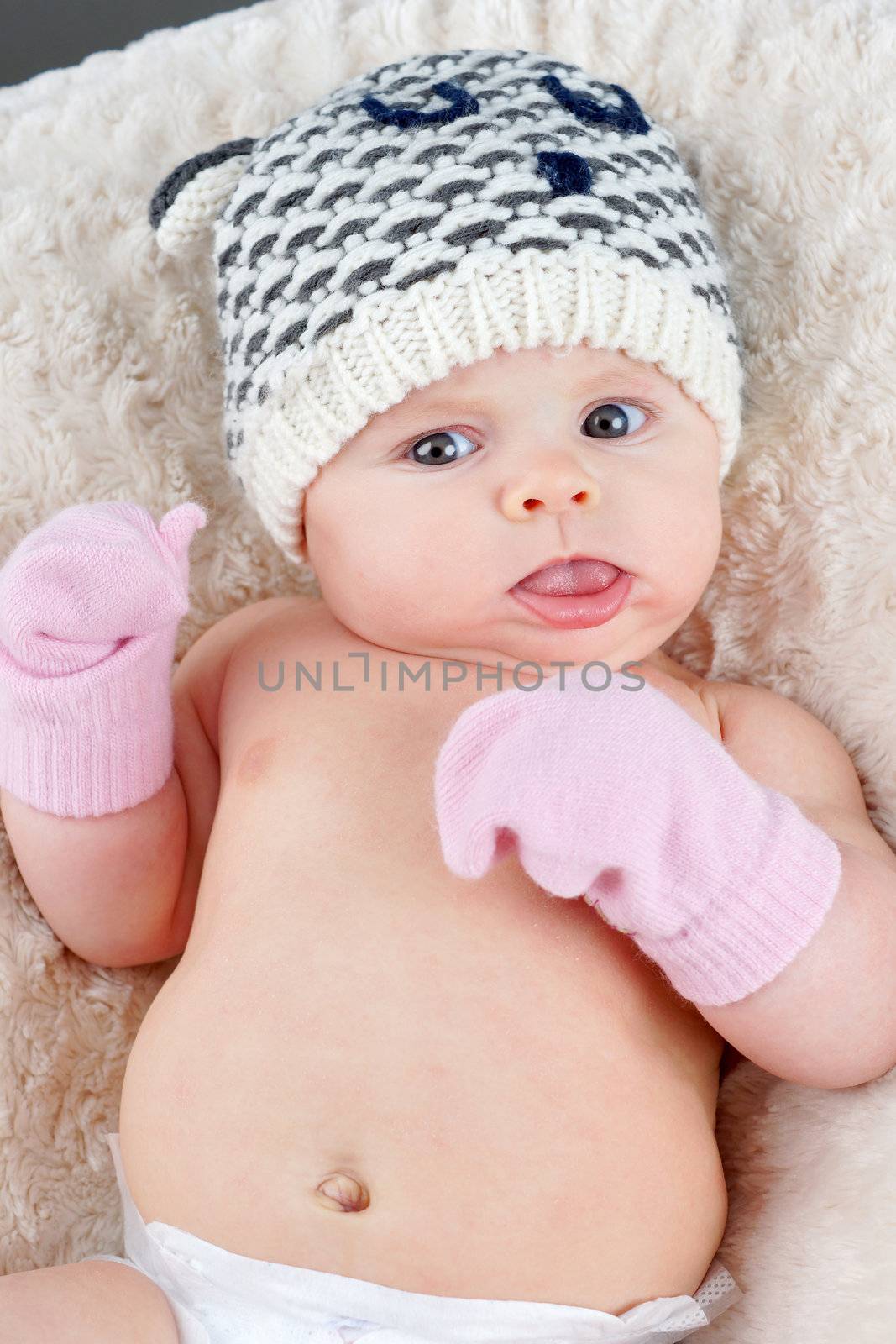 Baby girl portrait with funny face, hat and mittens