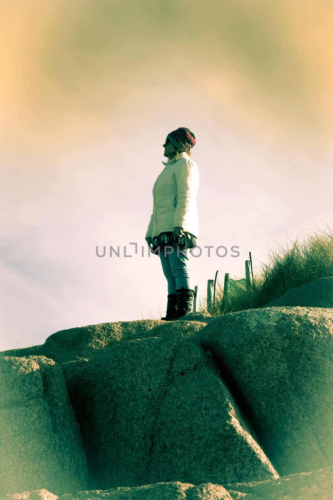 woman looking out to sea at the top of old natural rock formation on a beach in county Donegal, Ireland