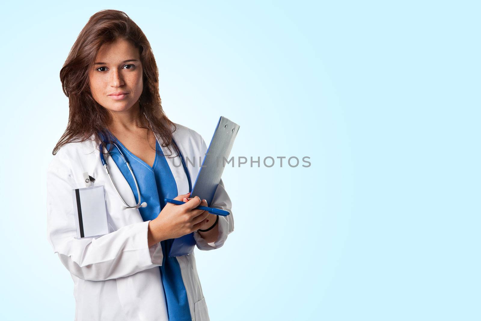 Young female doctor with scrubs and a stethoscope holding a notepad