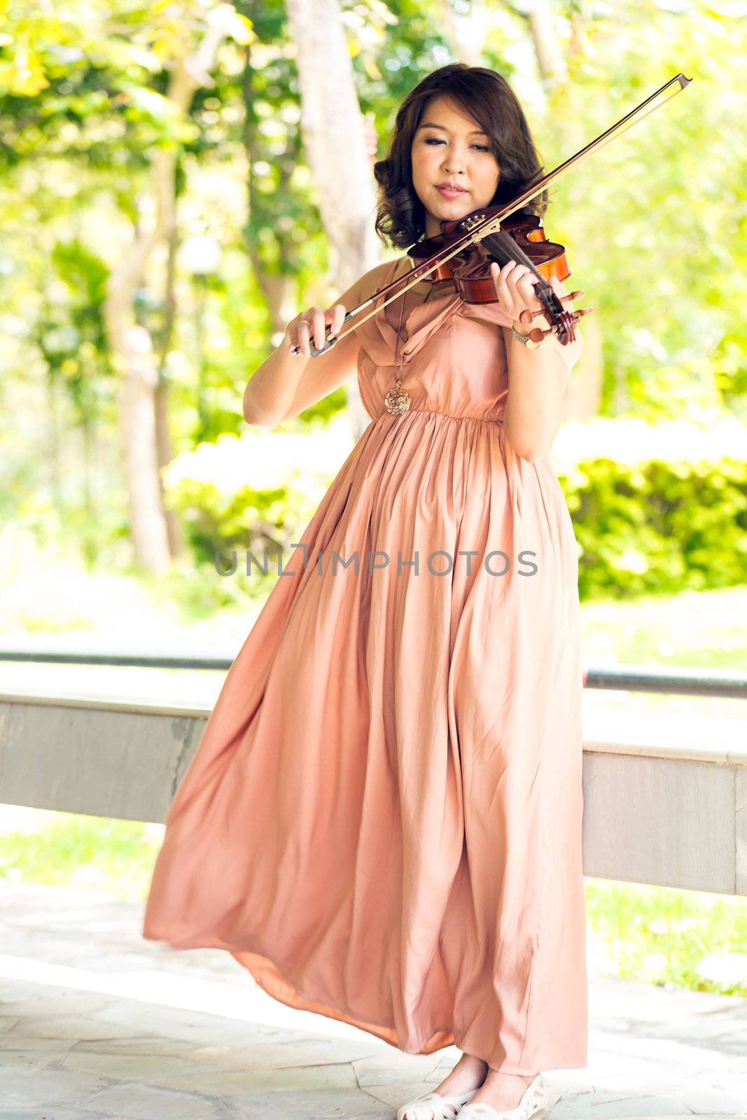 Young woman playing violin in garden