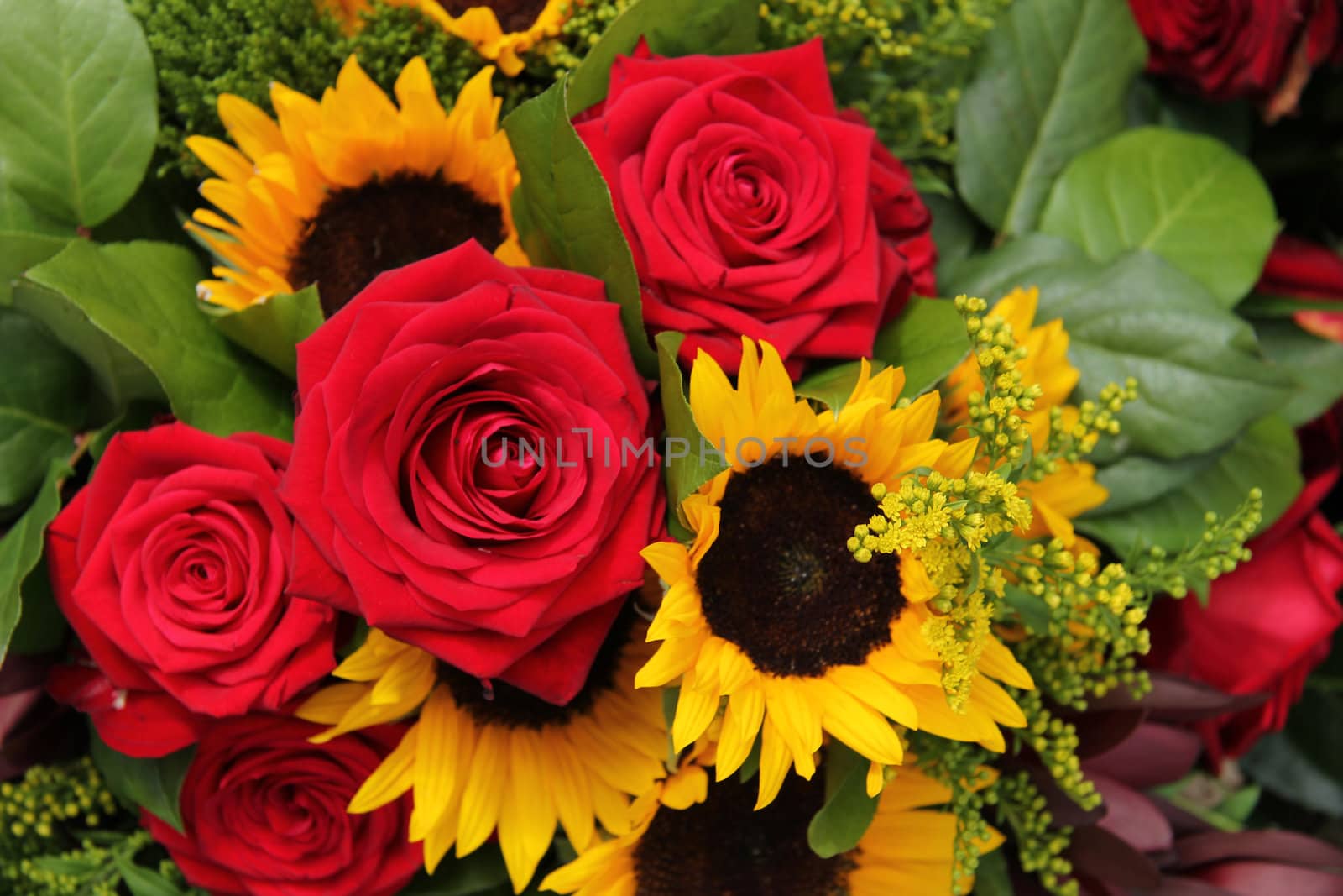 Red roses and sunflowers in a floral arrangement by studioportosabbia