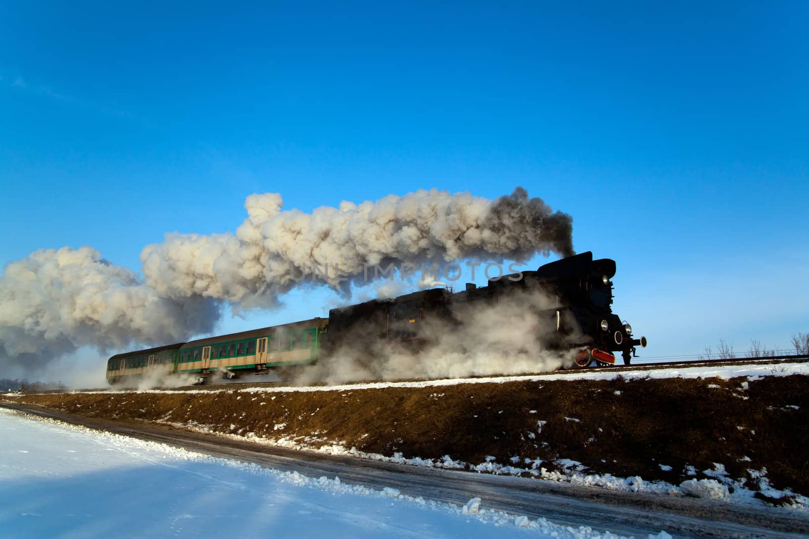 Vintage steam train puffing through countryside during wintertime
