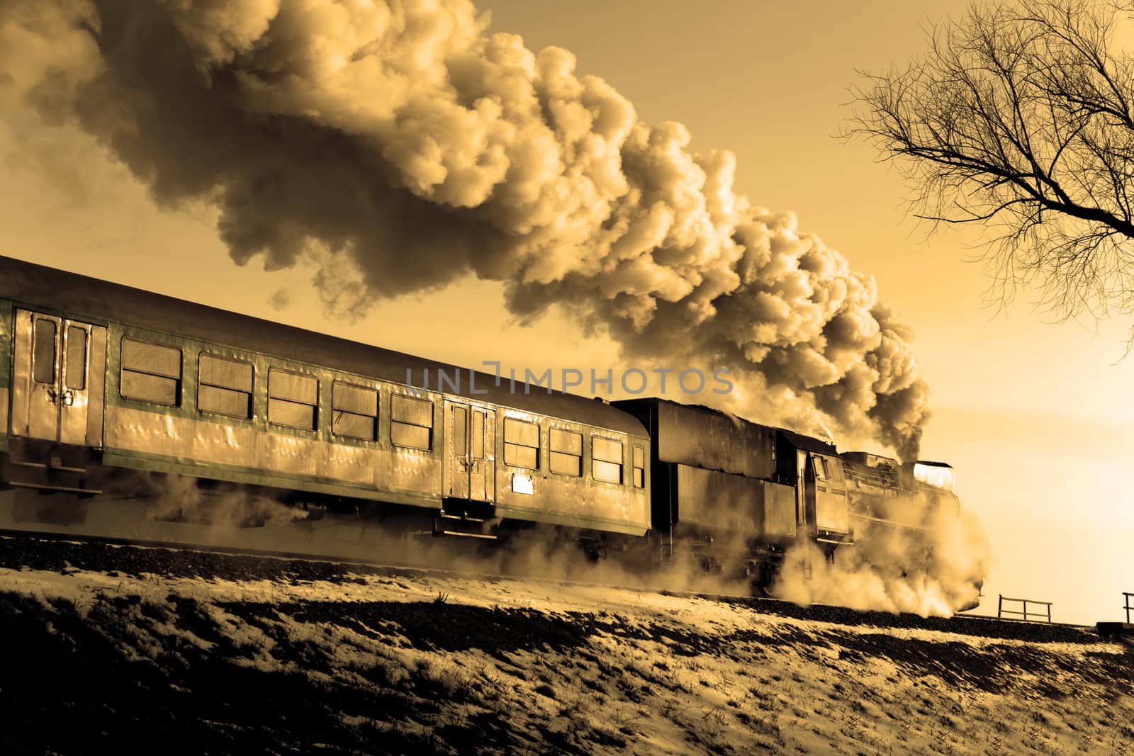 Vintage steam train puffing through countryside during wintertime
