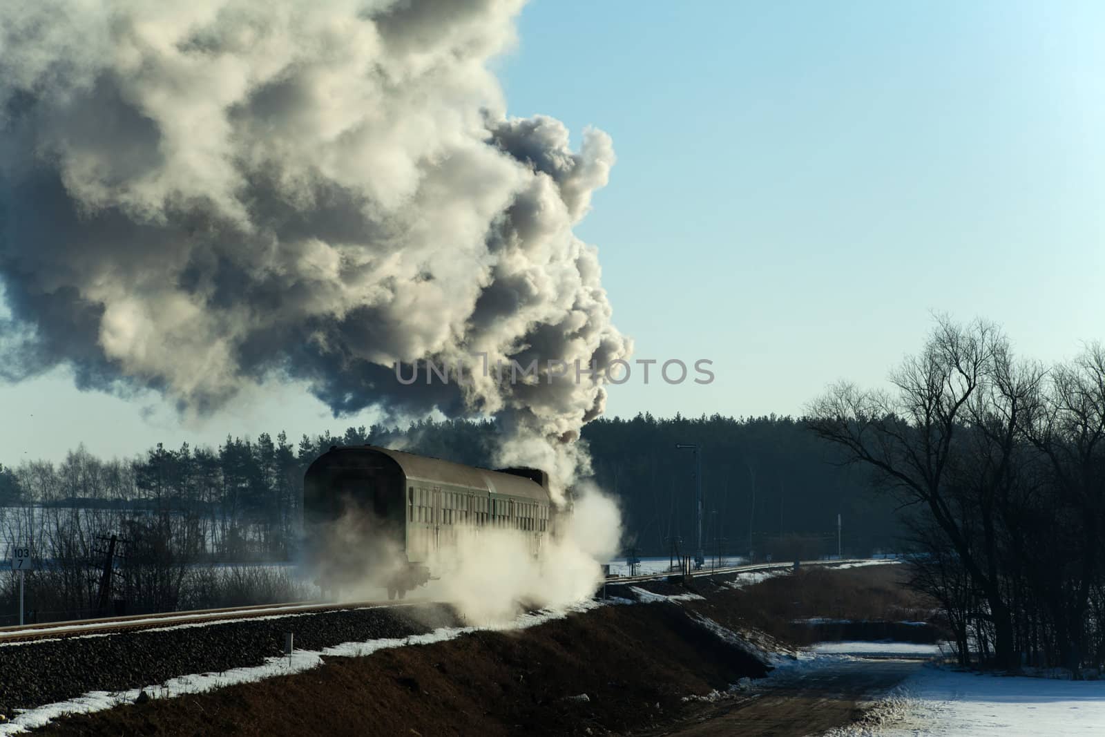 Vintage steam train puffing through countryside during wintertime
