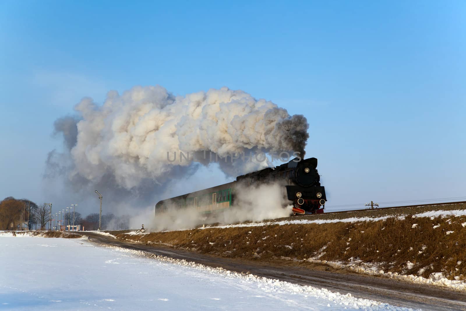 Vintage steam train puffing through countryside during wintertime
