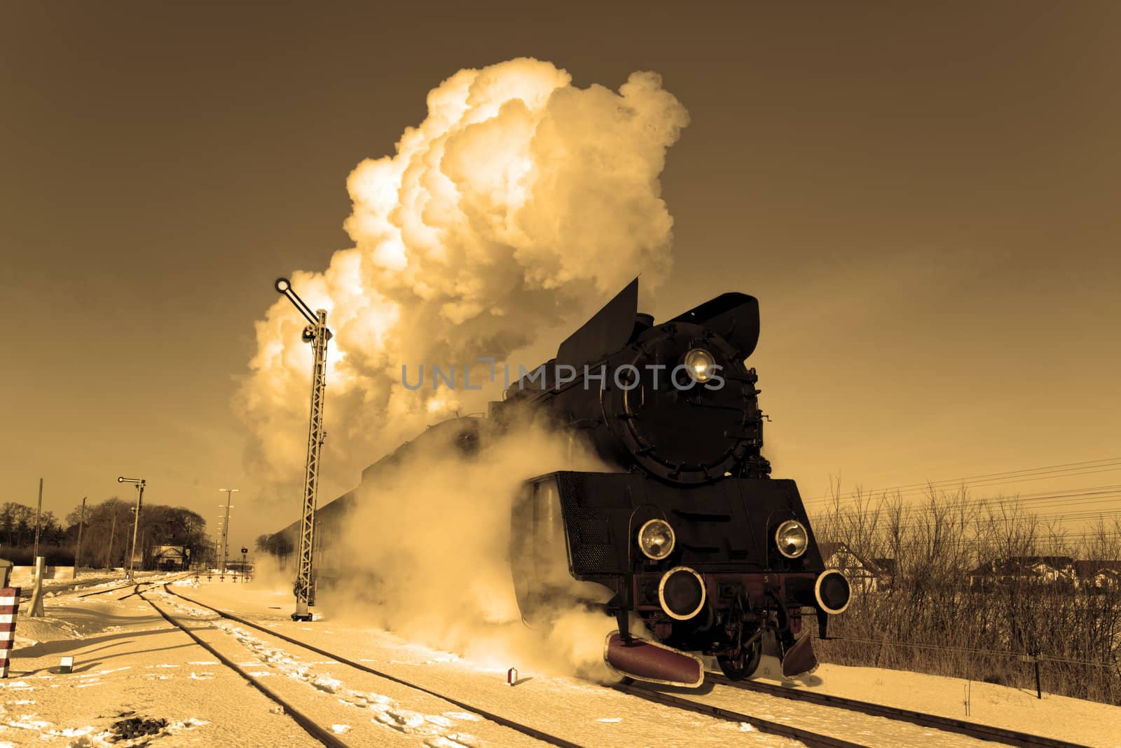 Vintage steam train puffing through countryside during wintertime
