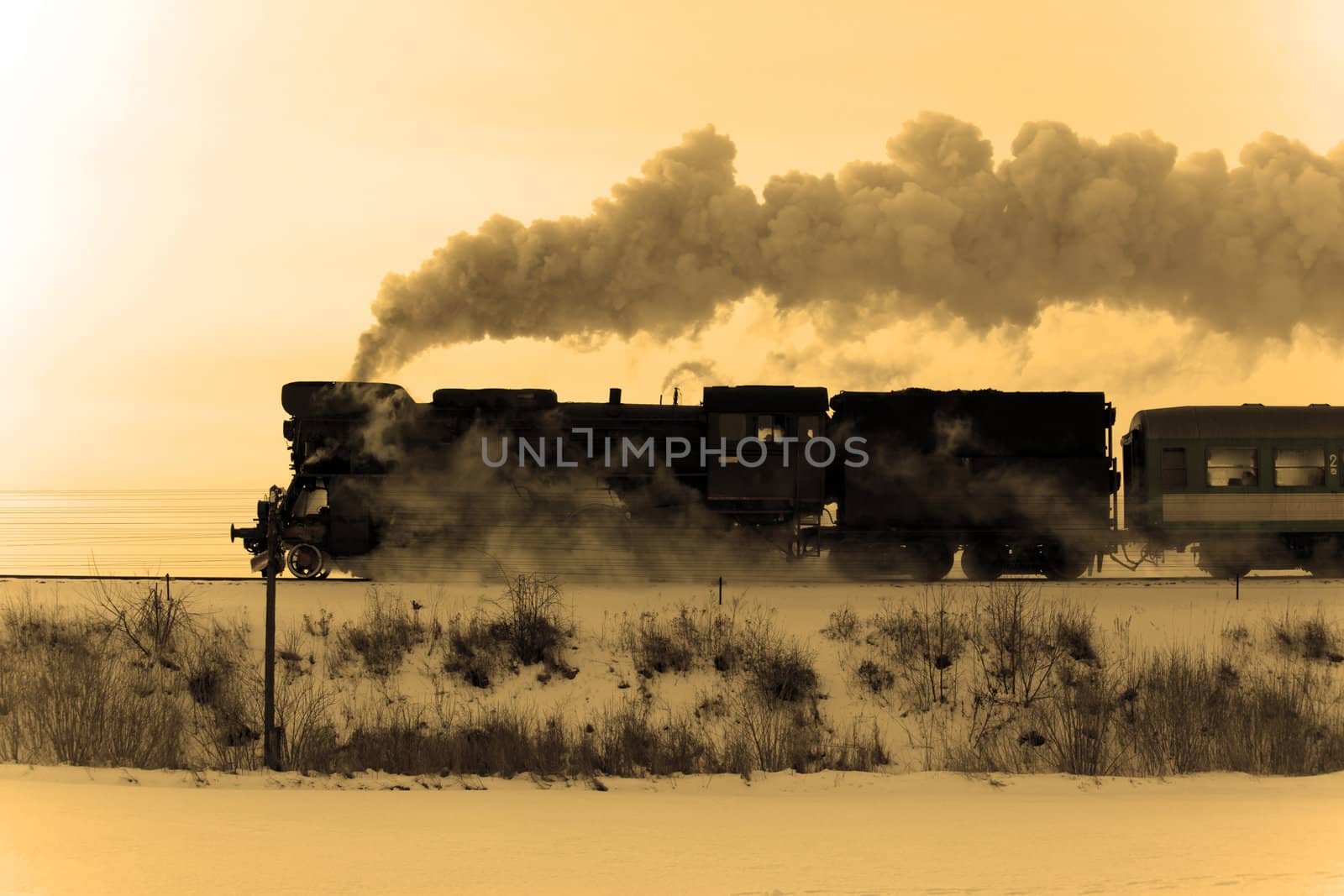 Vintage steam train puffing through countryside during wintertime
