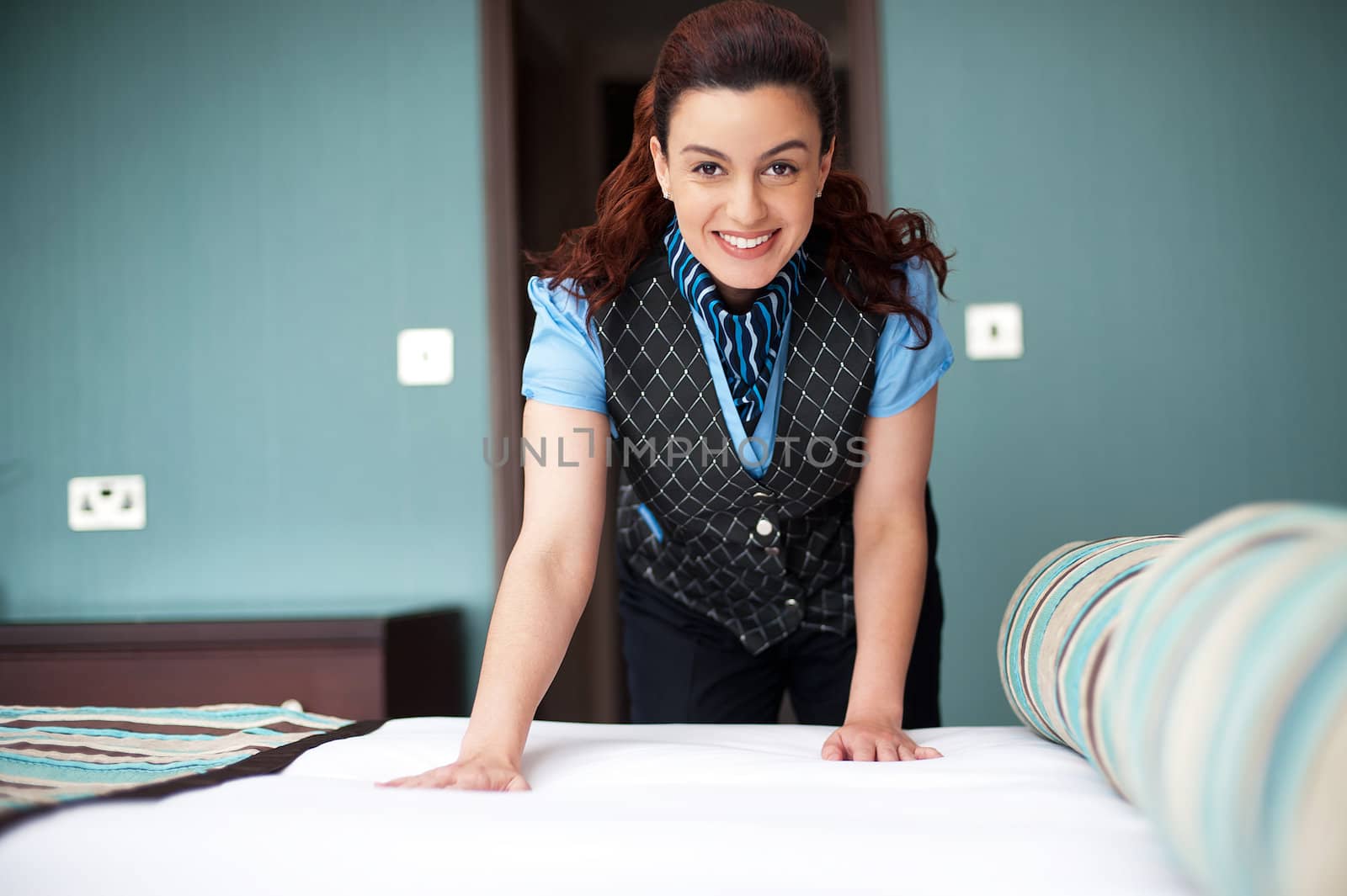 Smiling female executive giving final touches to master bedroom. Cheerfully working