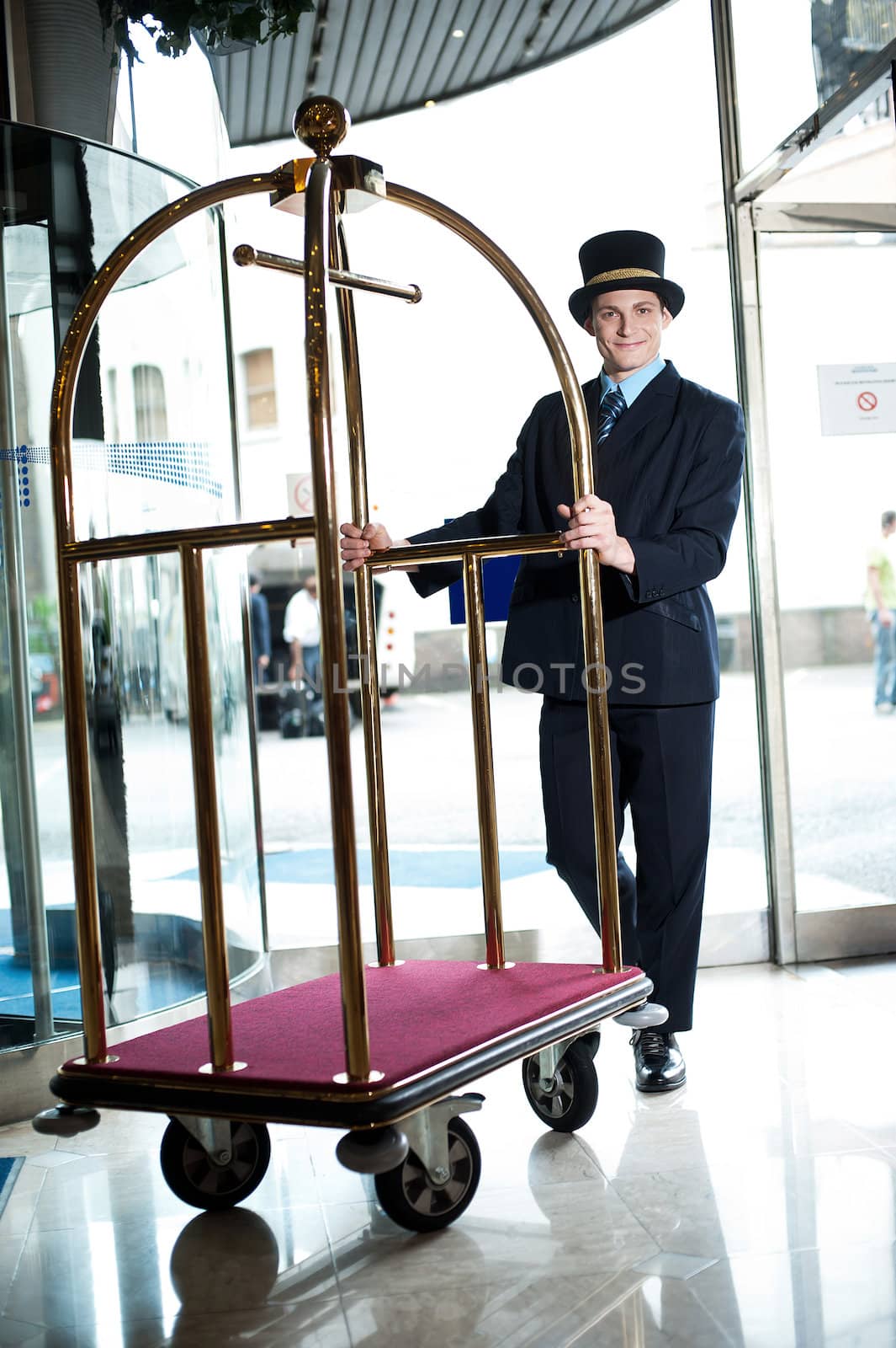 Profile shot of doorman holding cart at the entrance of hotel