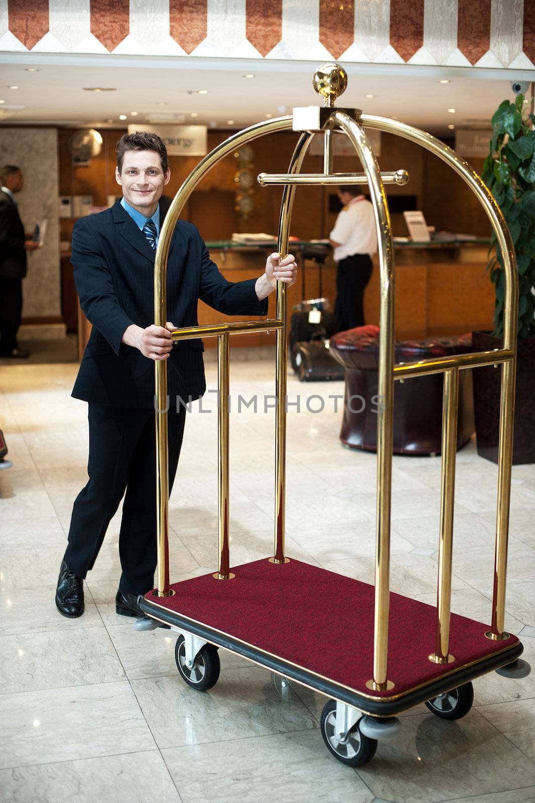 Casual shot of a concierge pushing  the cart in hotel lobby