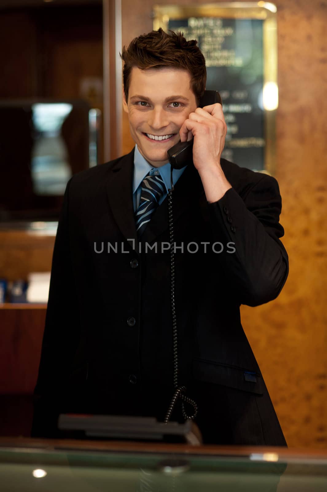 Calm and relaxed executive interacting over the phone and smiling at camera