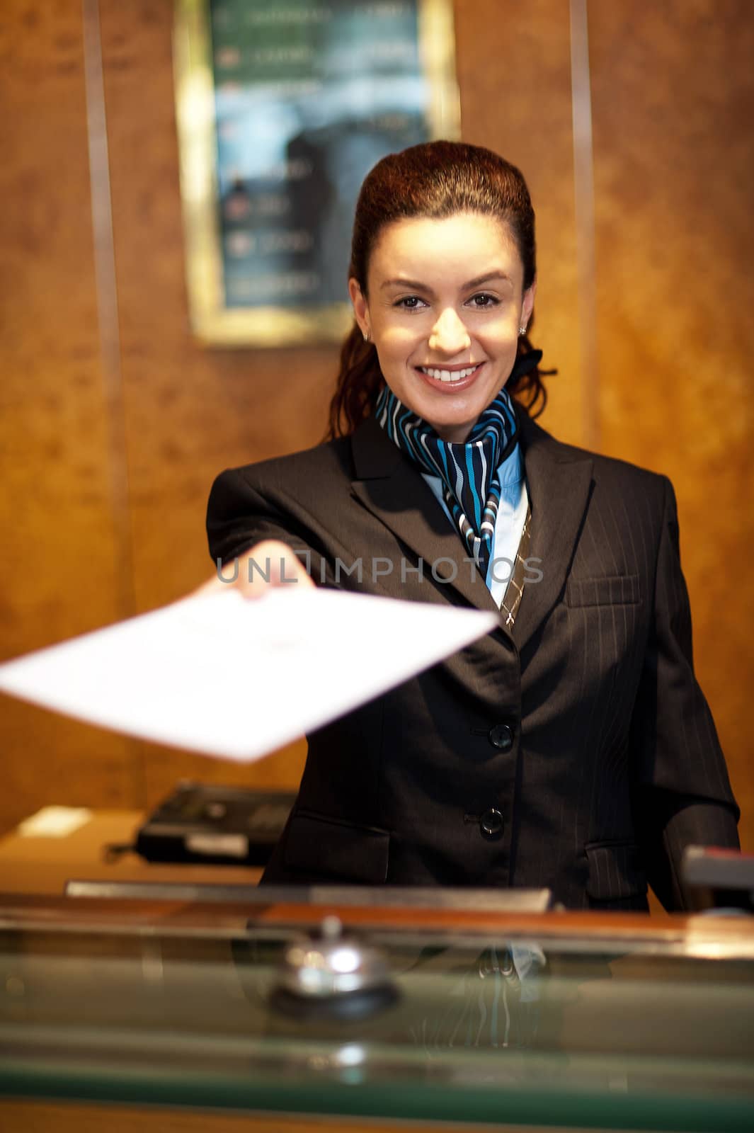 Cheerful female receptionist offering check-in papers to the customer