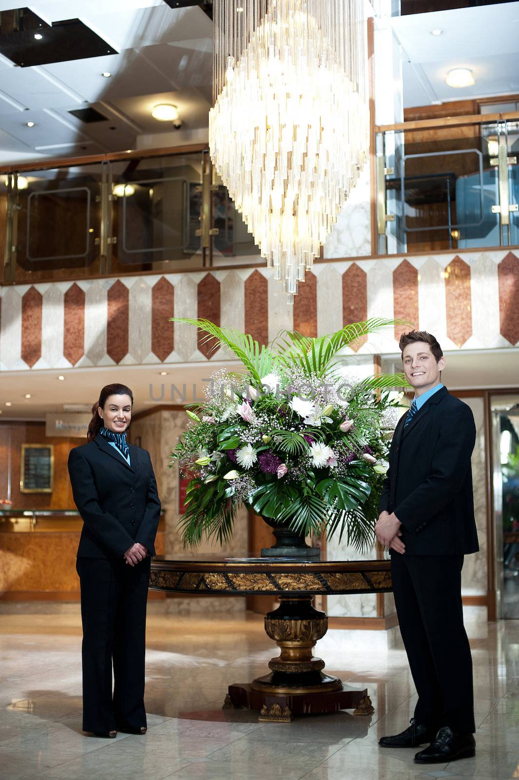 Smartly dressed front office executives posing under a chandler with flower vase as a centerpiece