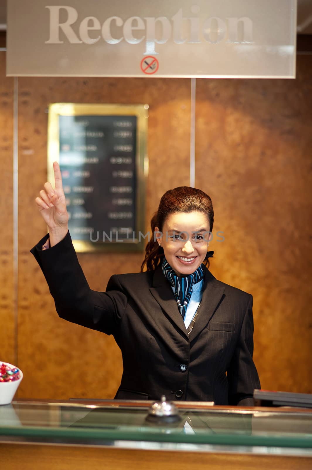 Beautiful female receptionist indicating upwards to show the direction instructions board