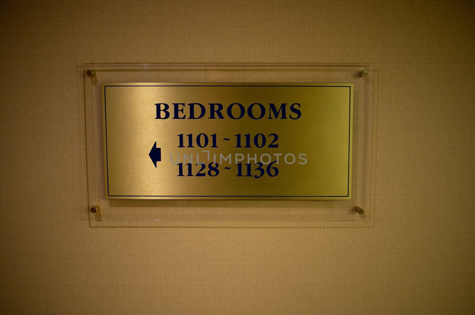 Yellowish brass board on wall indicating direction to the bedrooms