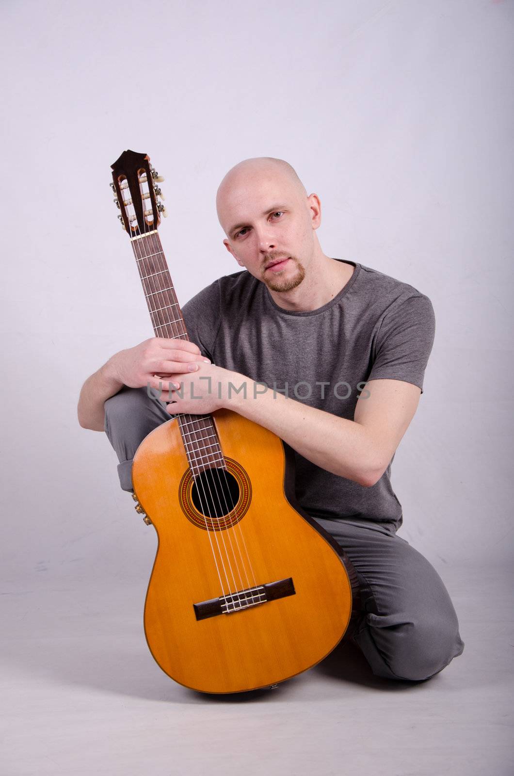 Nice bald guy with a guitar in the studio