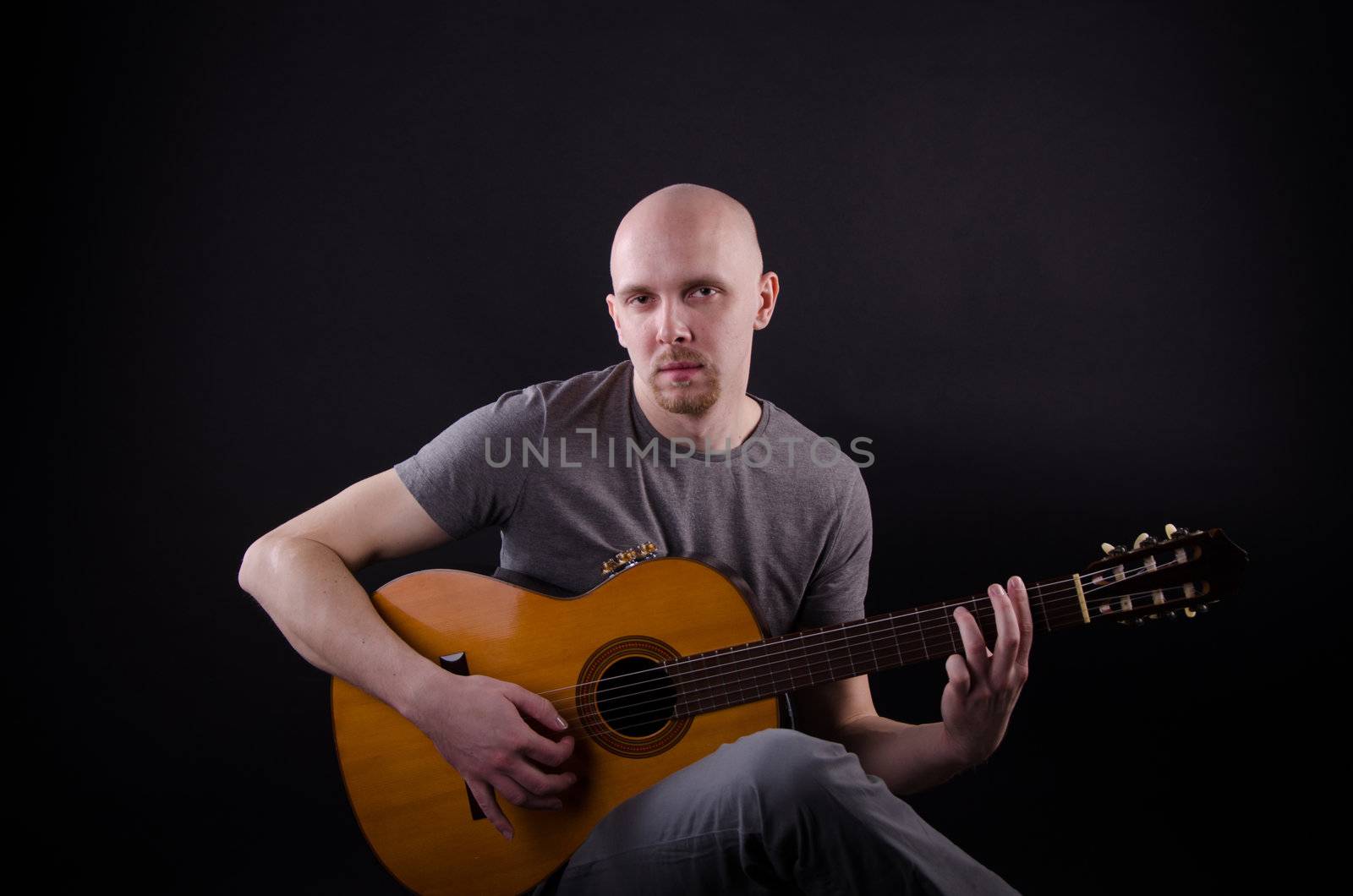 Nice bald guy with a guitar in the studio