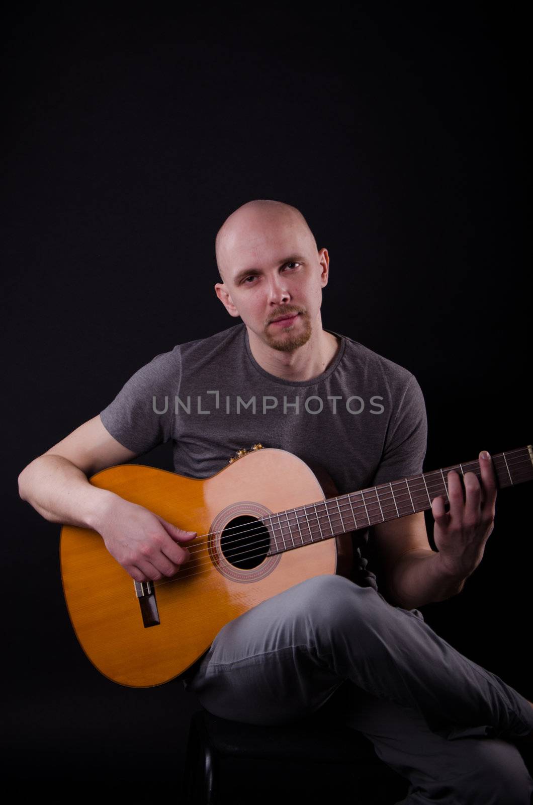 Nice bald guy with a guitar in the studio