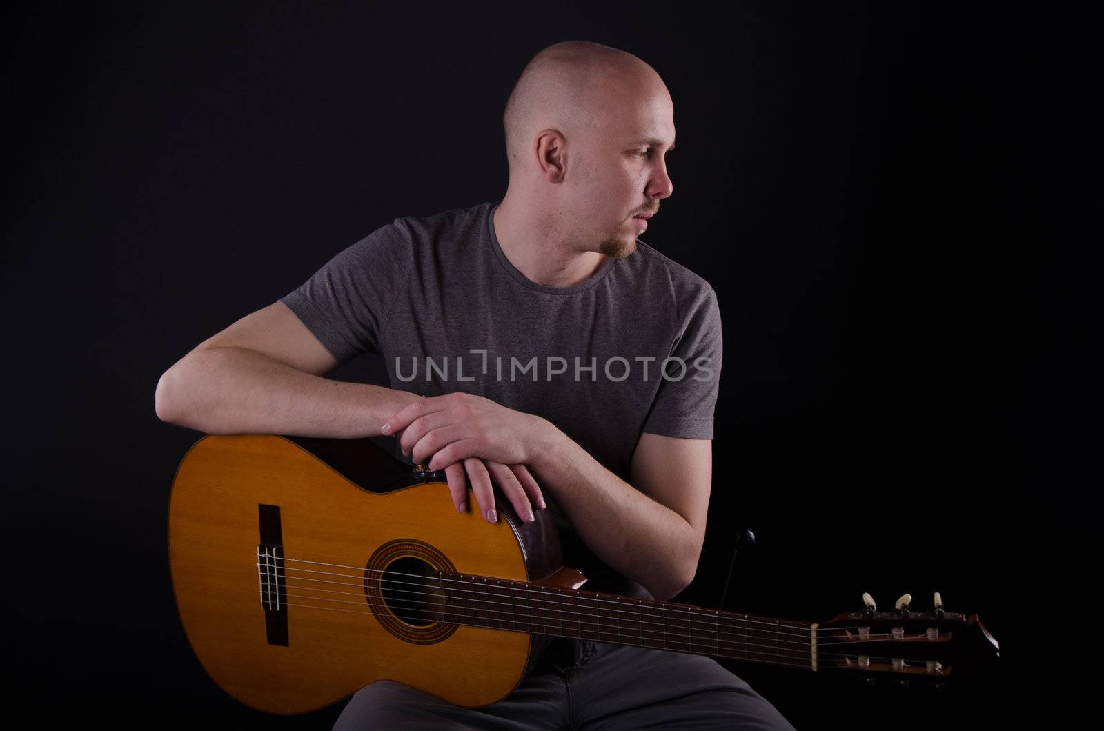 Nice bald guy with a guitar in the studio