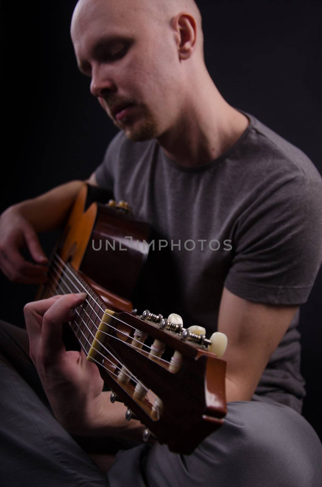 Nice bald guy with a guitar in the studio