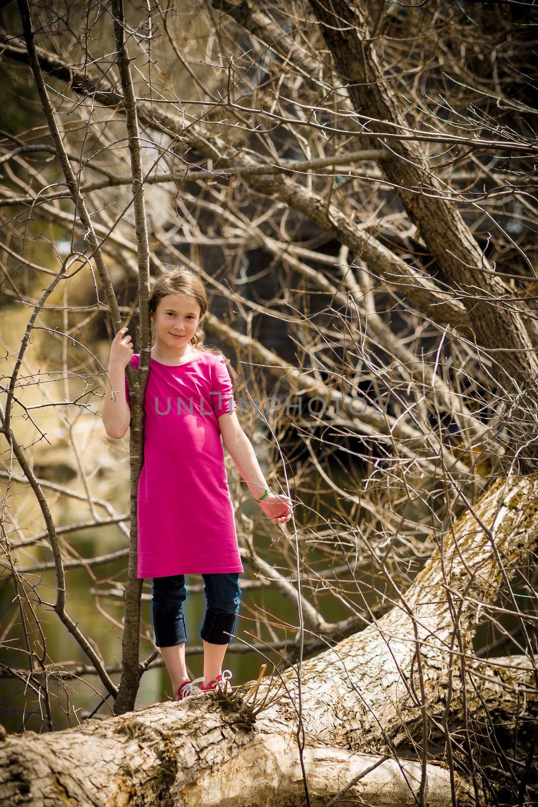 Girl standing on a tree over a river