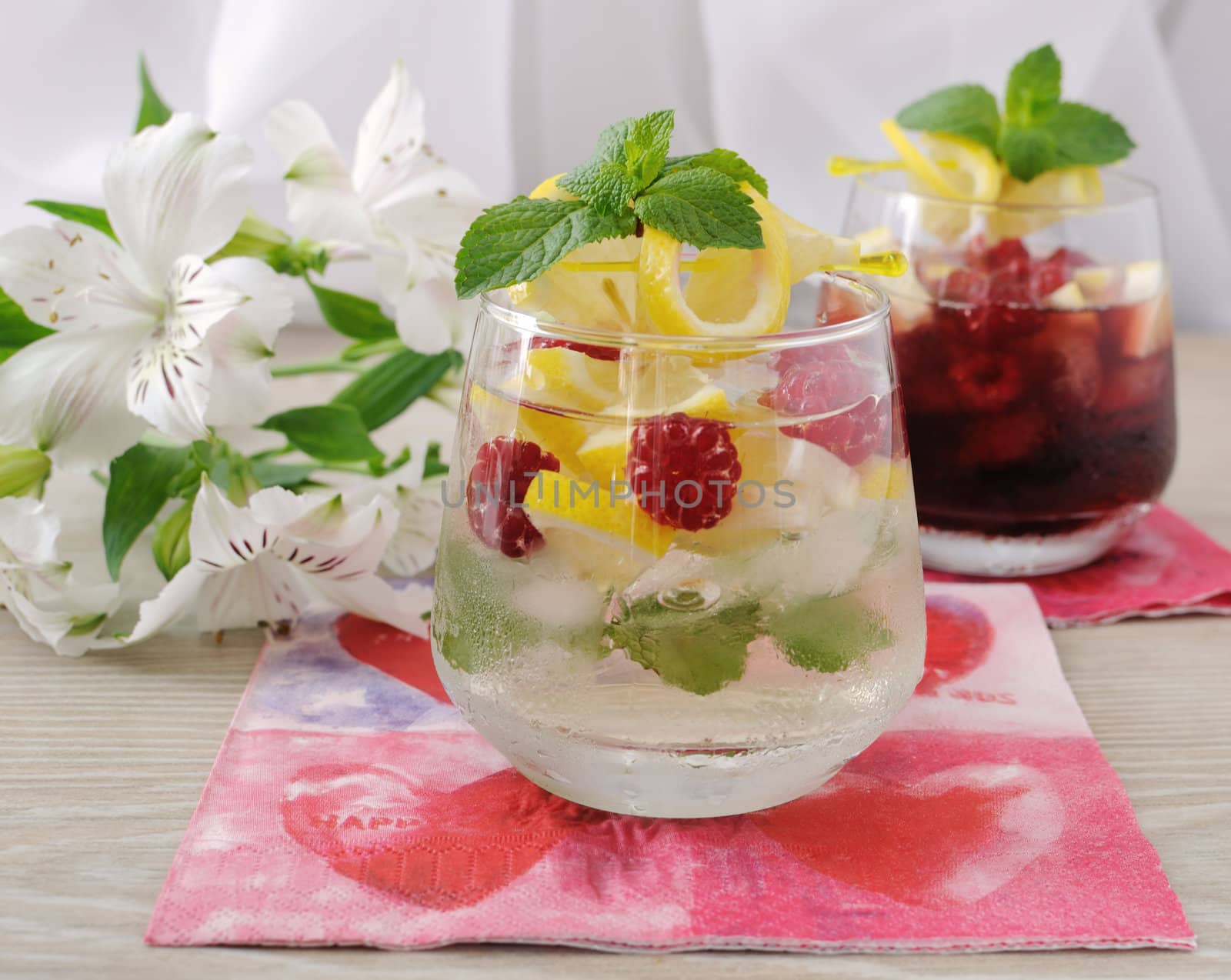 A glass of fresh homemade lemonade with mint and raspberries
