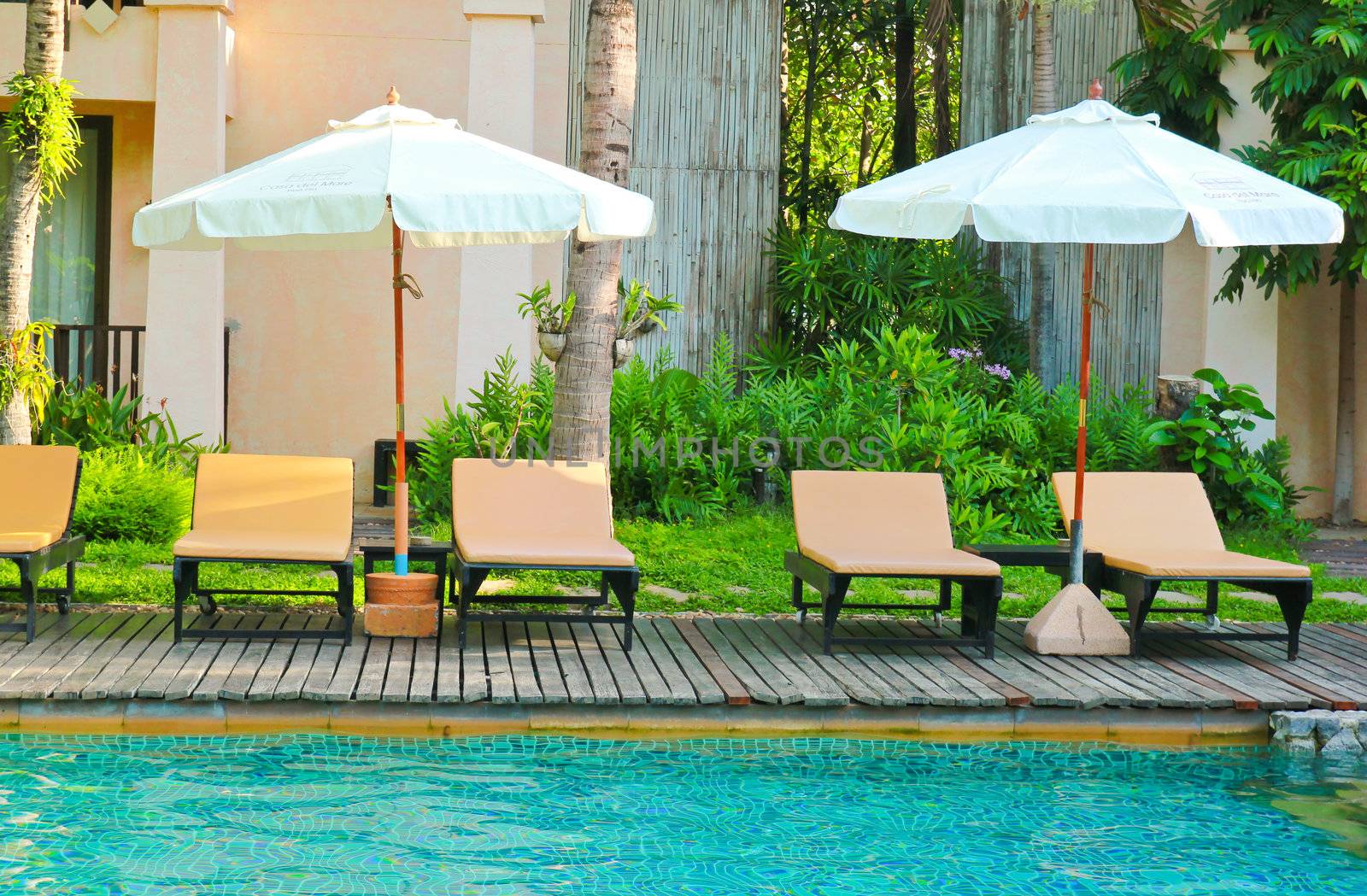 Beach chairs and umbrella side swimming pool  by nuchylee