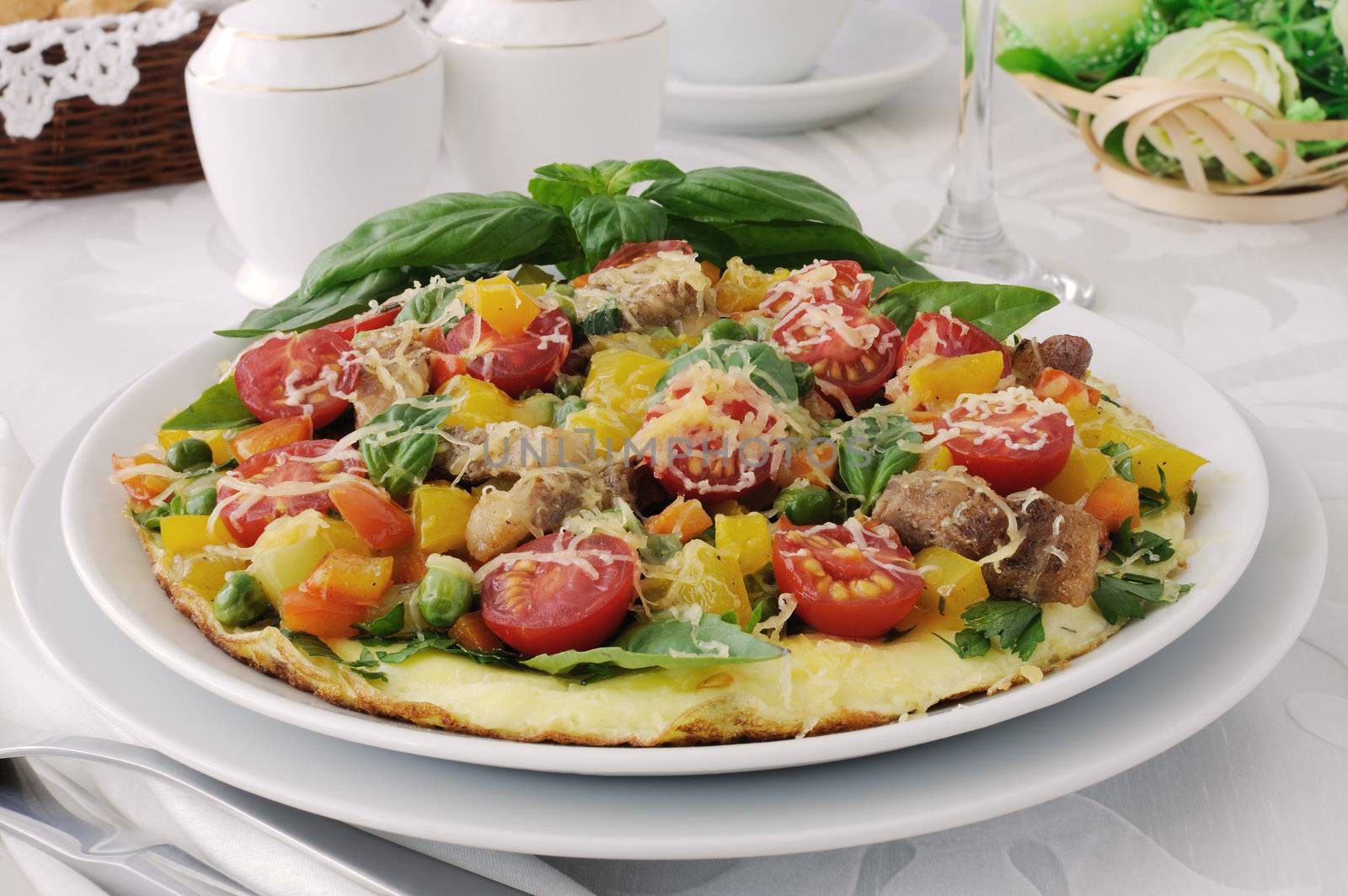 Omelet with vegetables and slices of bacon and cheese with basil