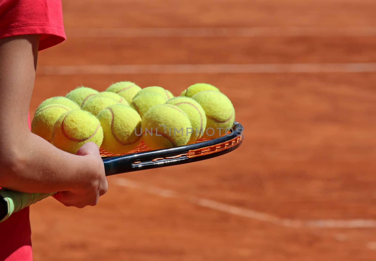 sportsman holding tennis racket with several balls on it