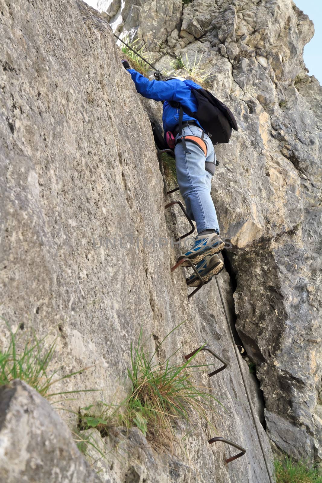 female climber with white helmet on Sass de Rocia via ferrata, italian Dolomites