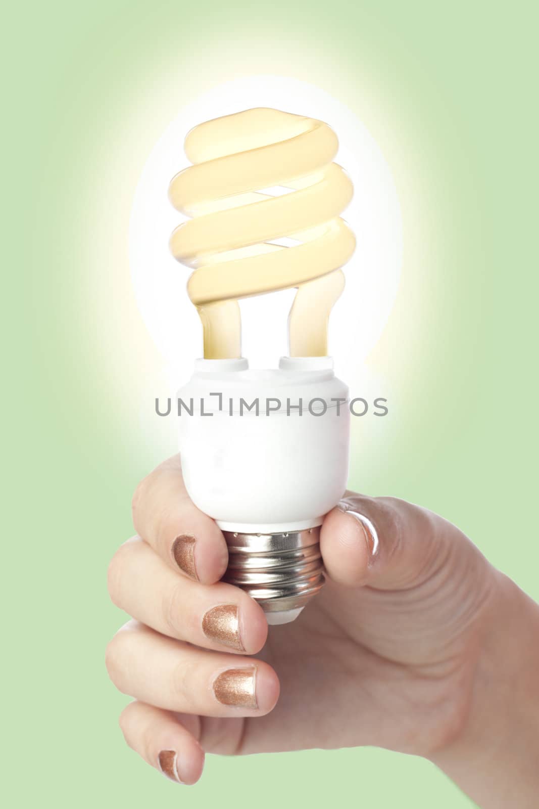 Close-up image of a hand holding a glowing fluorescent bulb isolated on a green background