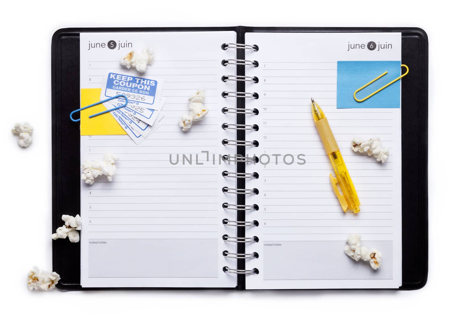 Image of notebook organizer with paper clips, pop corn, ball pen against white background