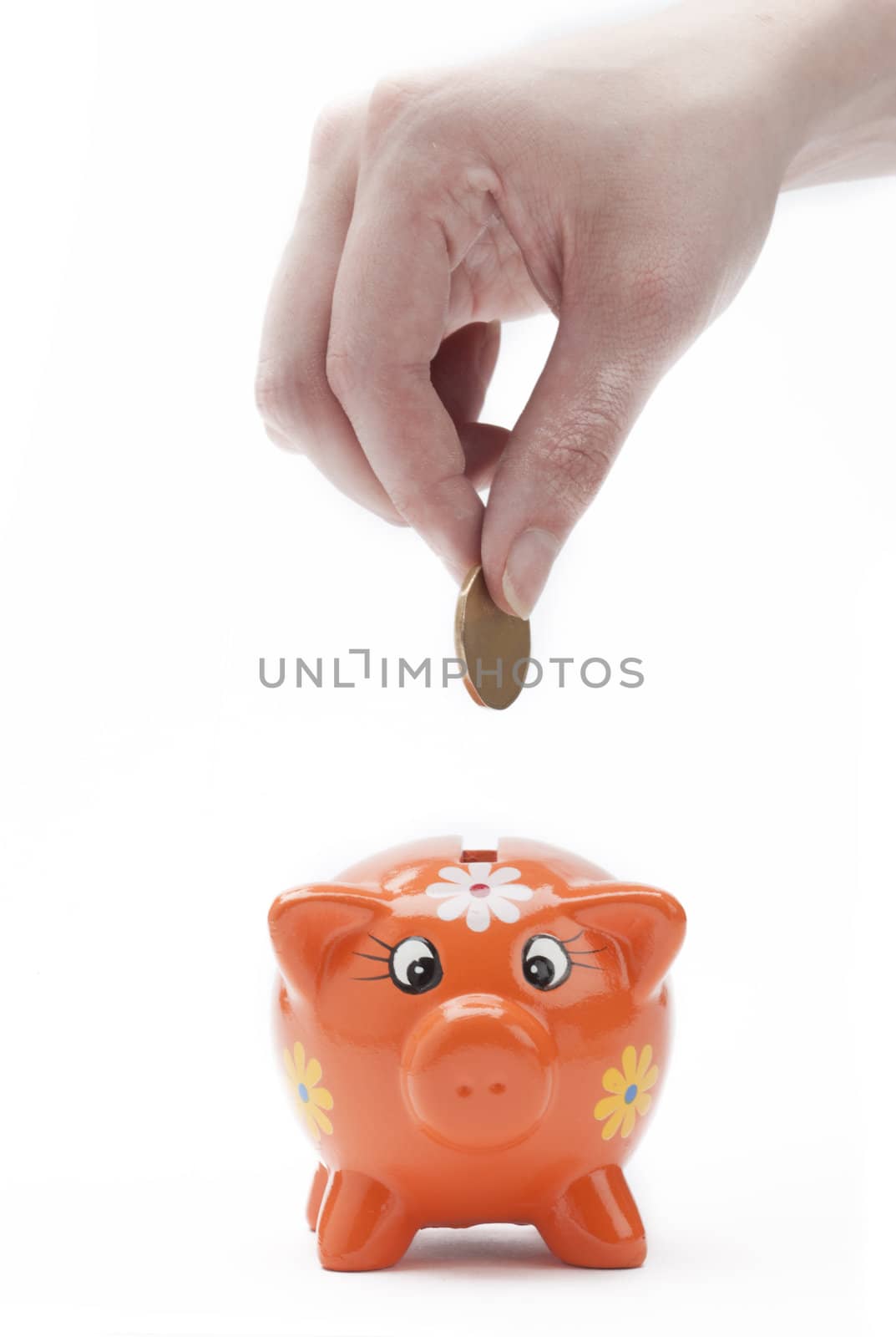 Someone putting coins into an orange piggy bank