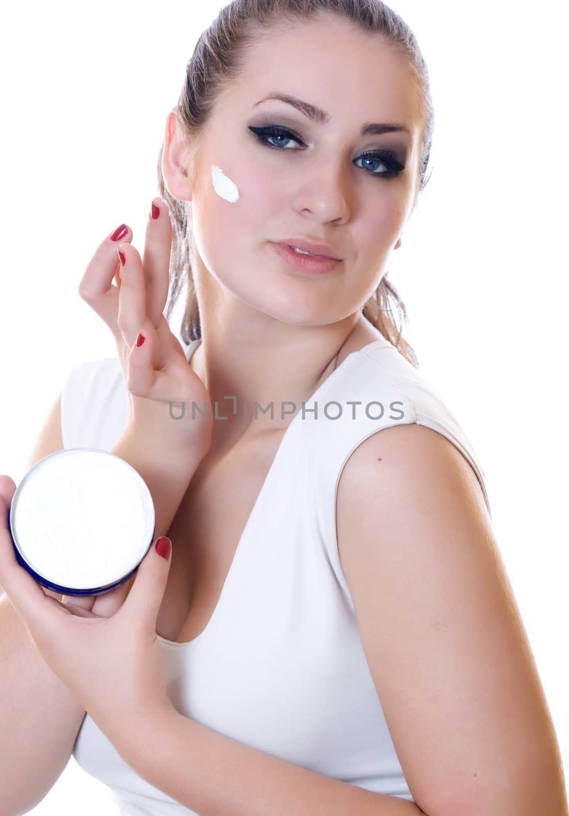 Portrait of young beautiful woman applying moisturizer cream on her face, isolated on white background