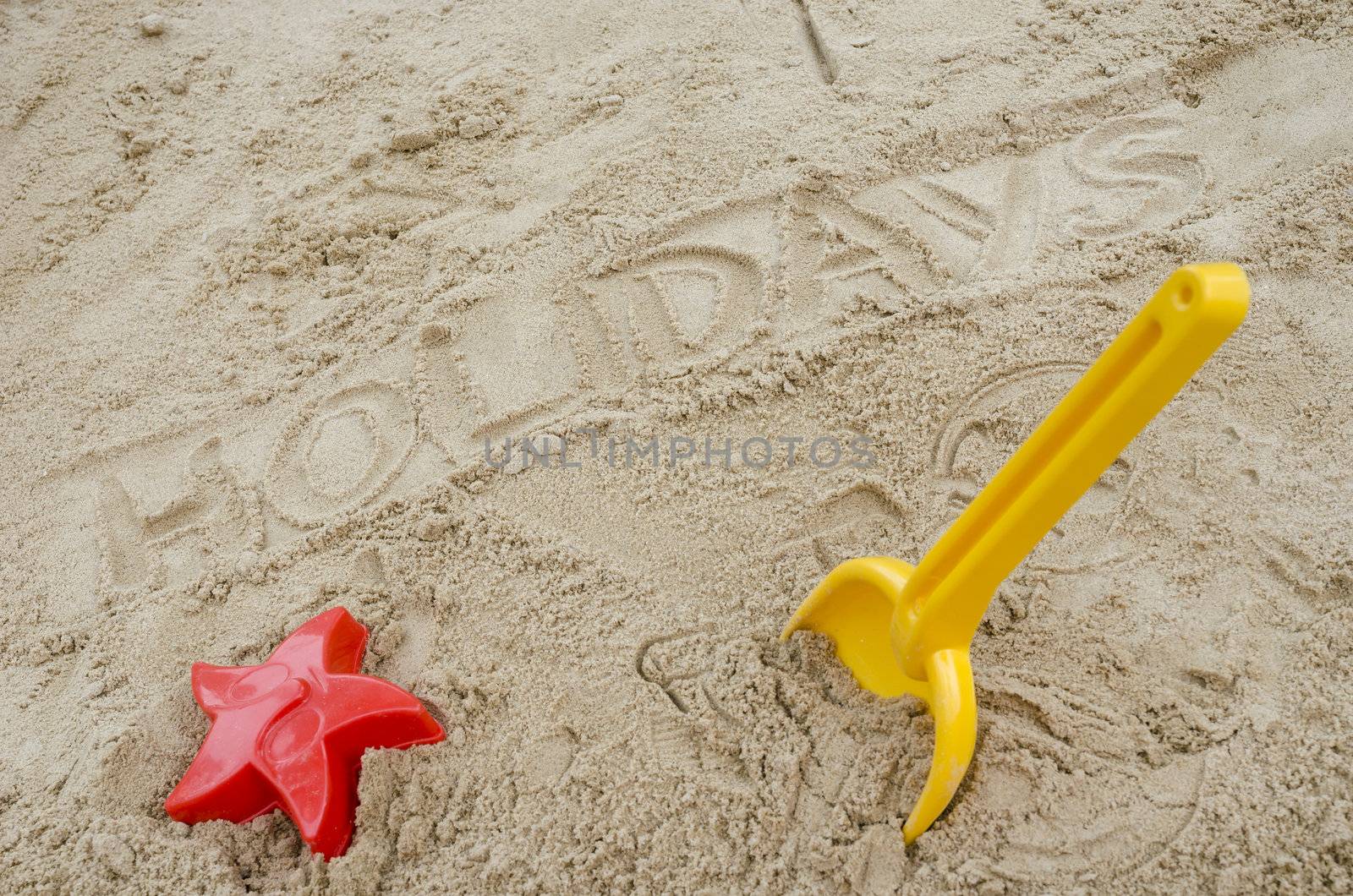 Word holidays written in sand. Concept of happy summer holiday.