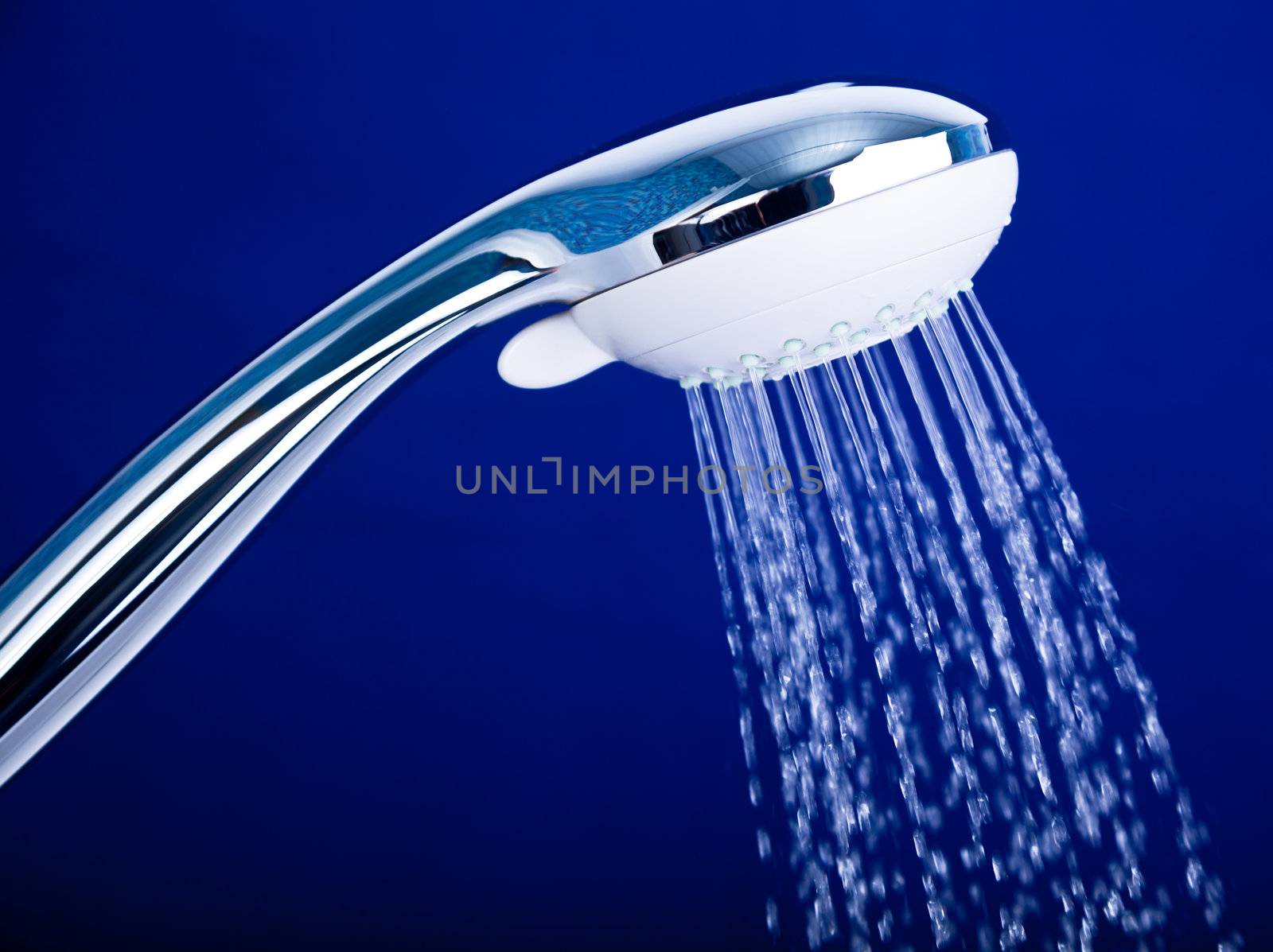 Shower head with running water against blue background