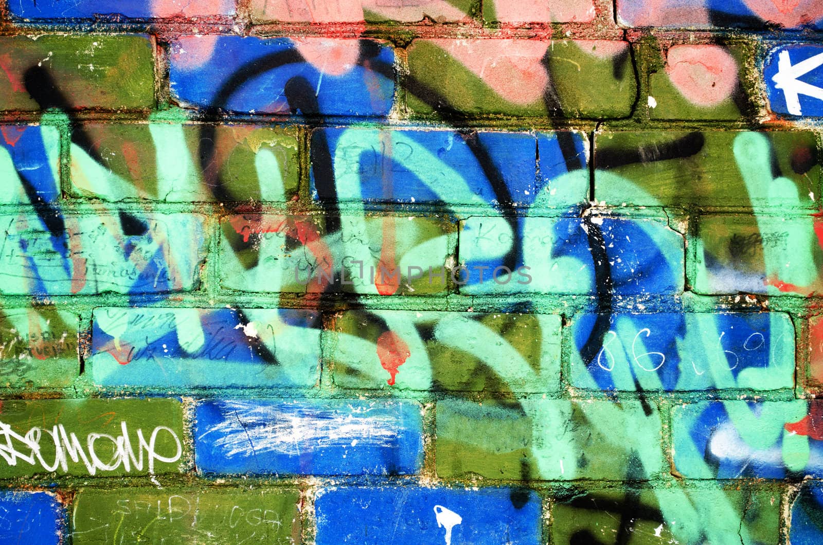 colorful painted brick wall with notes and marks of vandalism. urban background.