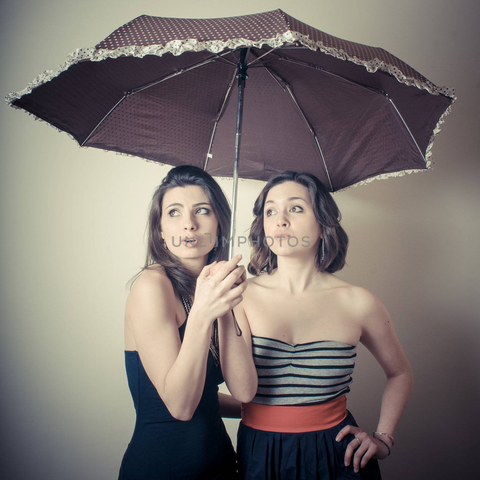 vintage portrait of two young women with umbrella on white background