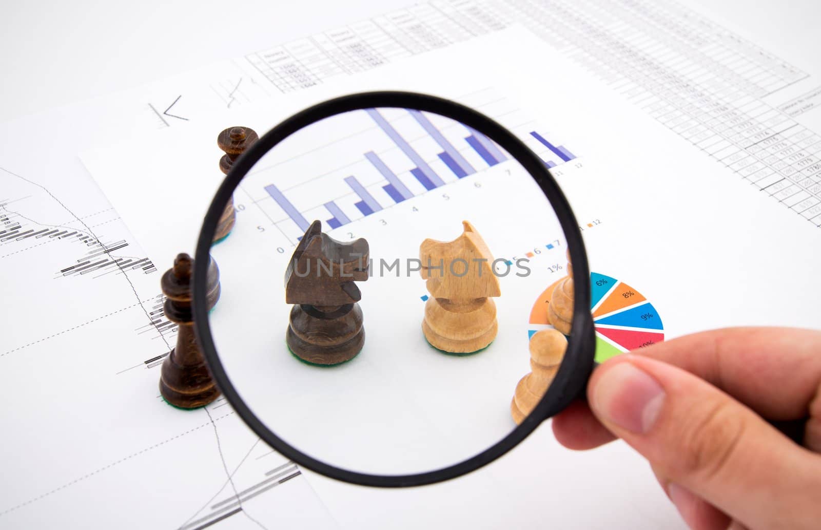 Business concept with magnifier and chess pieces on colorful background