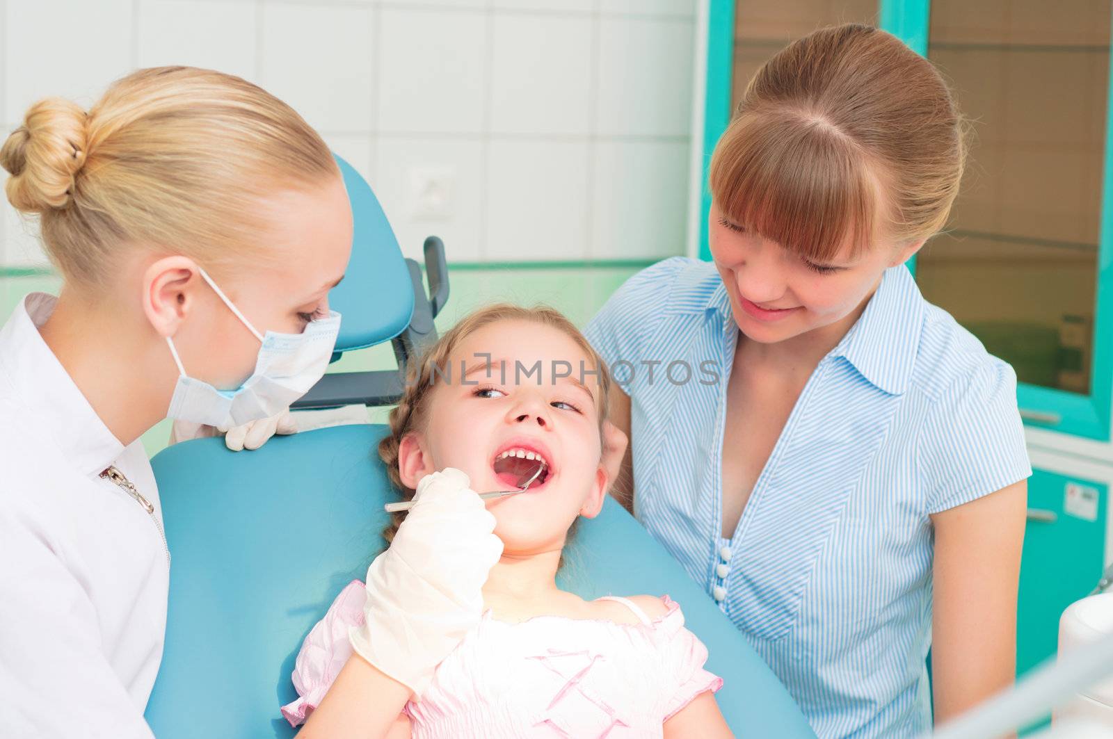 female dentists examines a child, my mother was sitting beside him and soothes baby