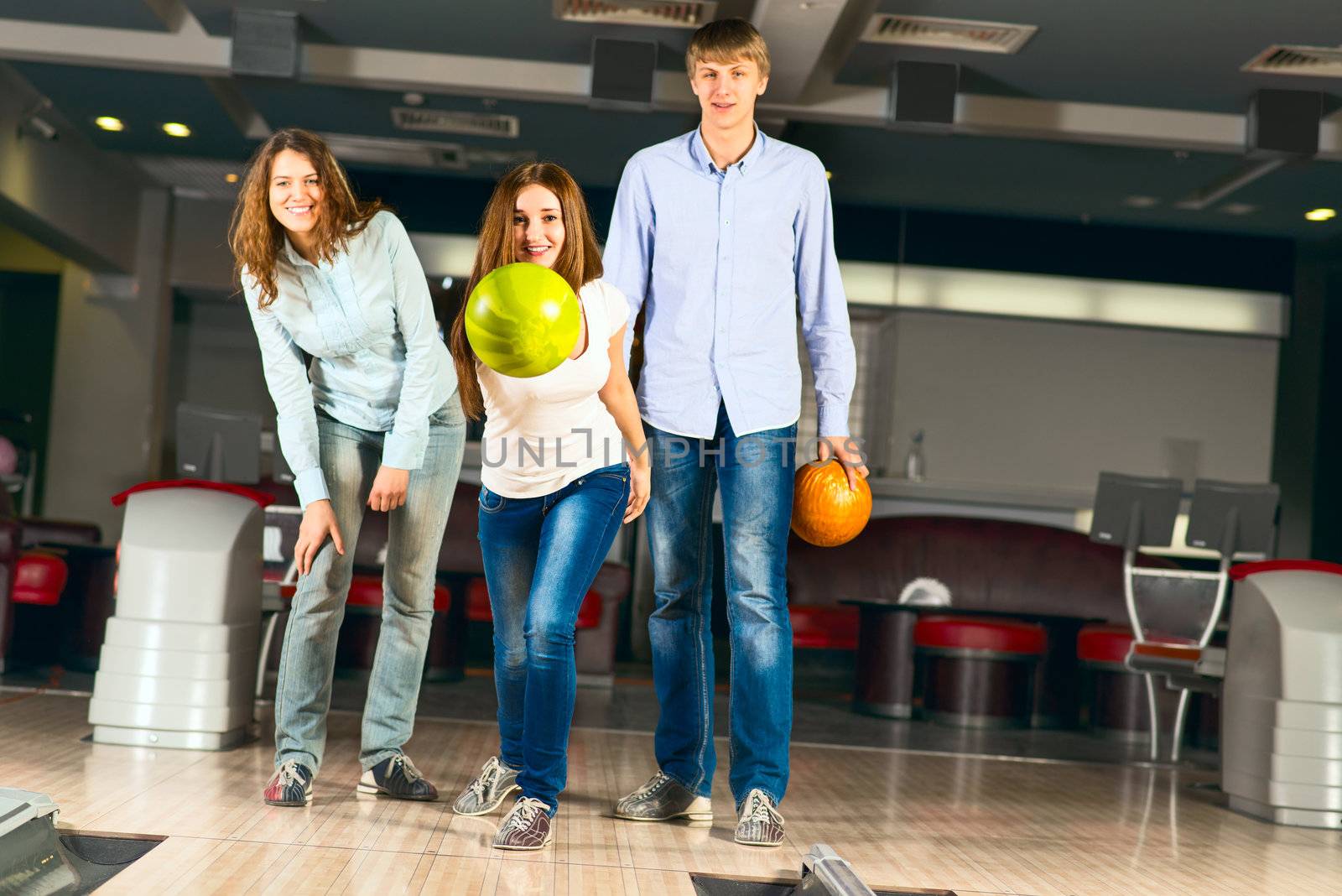 Group of young friends playing bowling, spending time with friends