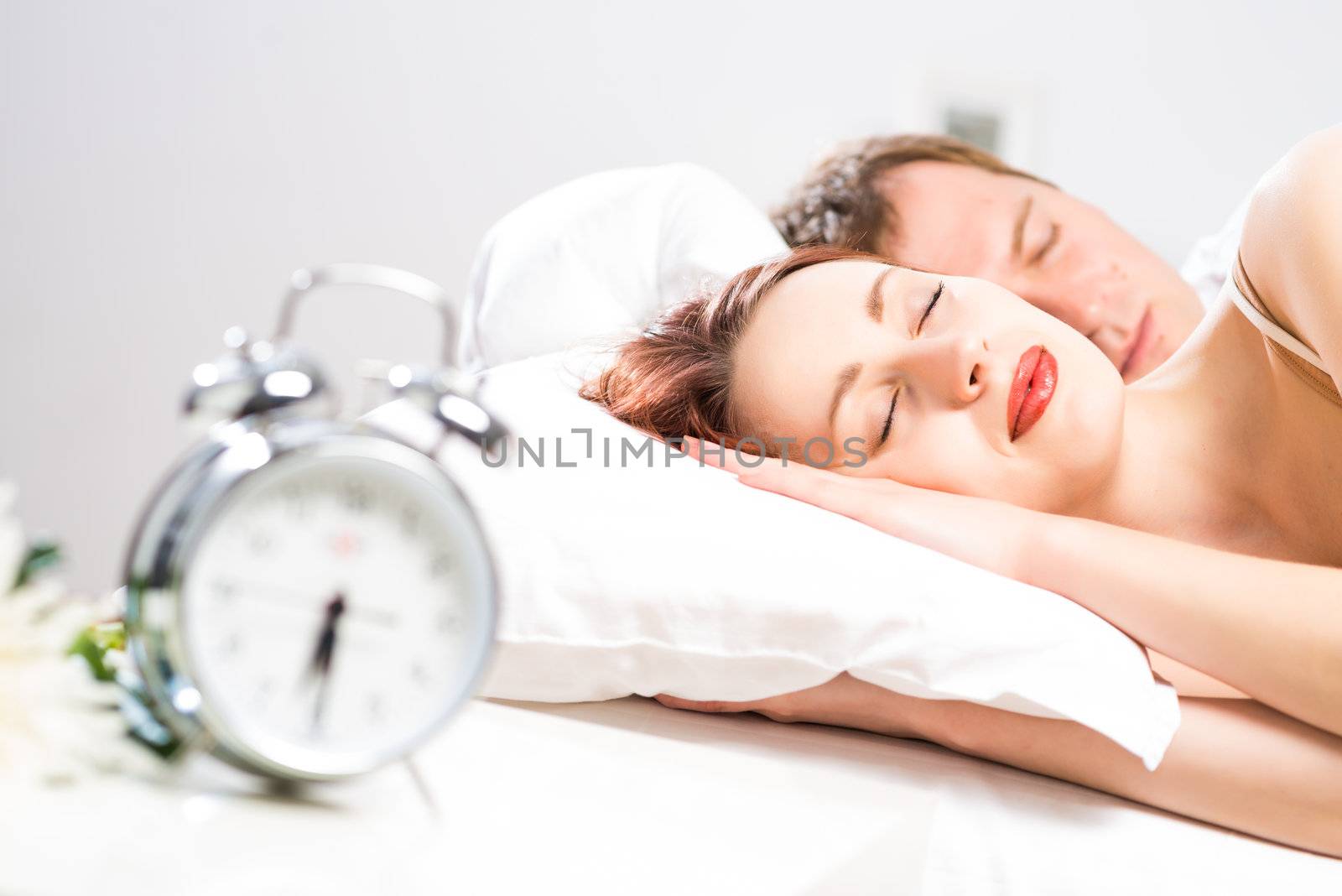 young beautiful woman sleeping on the bed with her husband