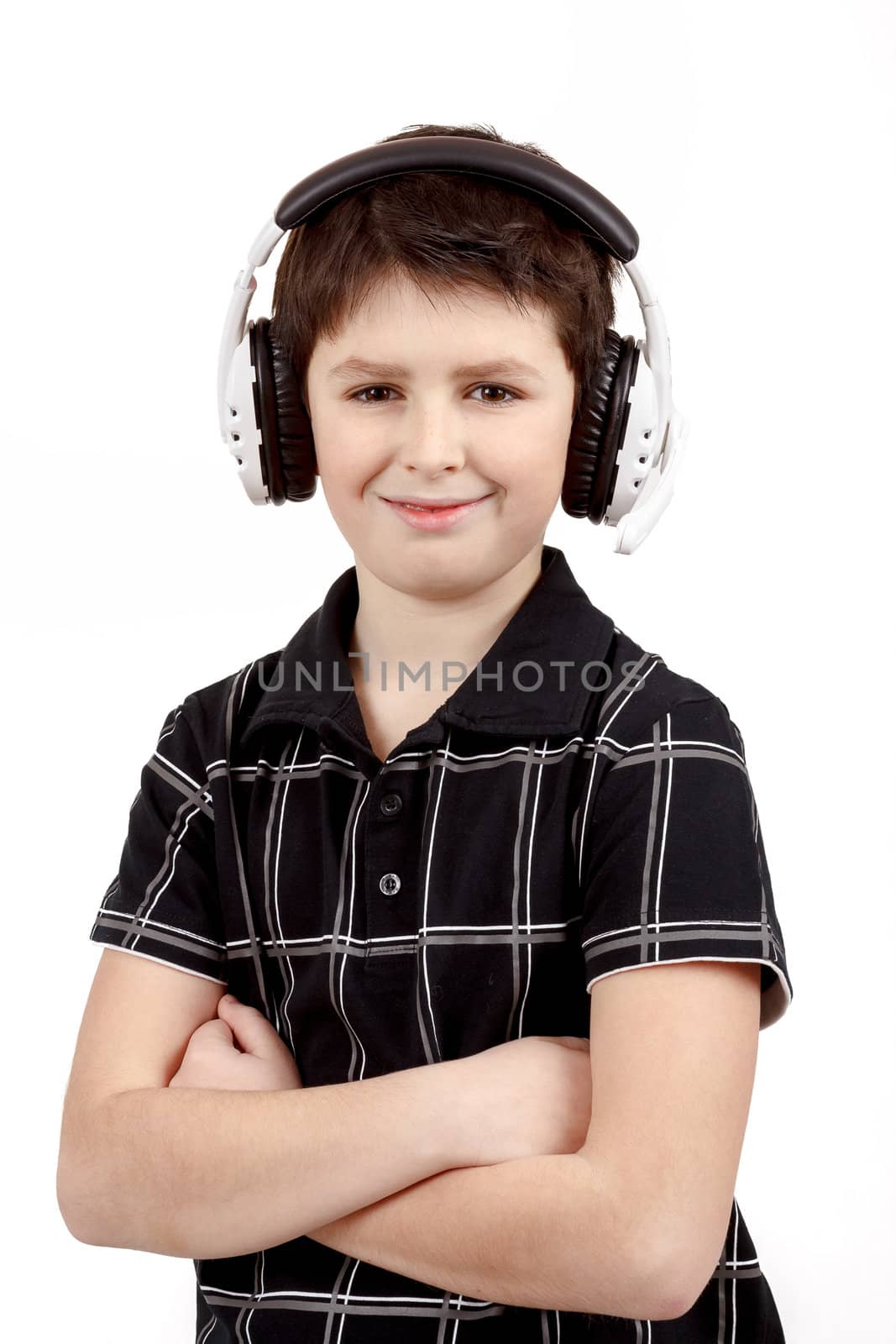Portrait of a happy smiling young boy listening to music on headphones against white background 